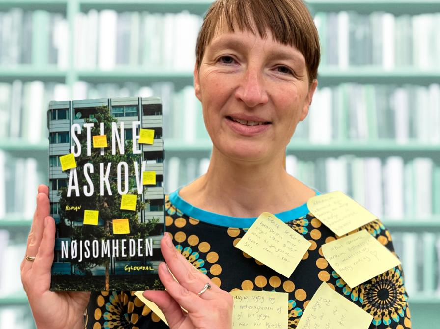 Litteraturformidler Bettina Schnegelsberg-Laursen holder bogen 'Nøjsomheden'. Bettina har seks gule post-it sedler på sig, så hun matcher forsiden af bogen