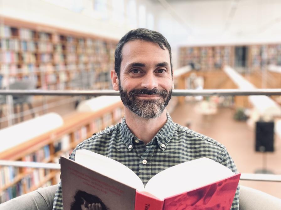 Litteraturformidler Benoit Enguerran Petit sidder i stol og læser bogen 'Sult'