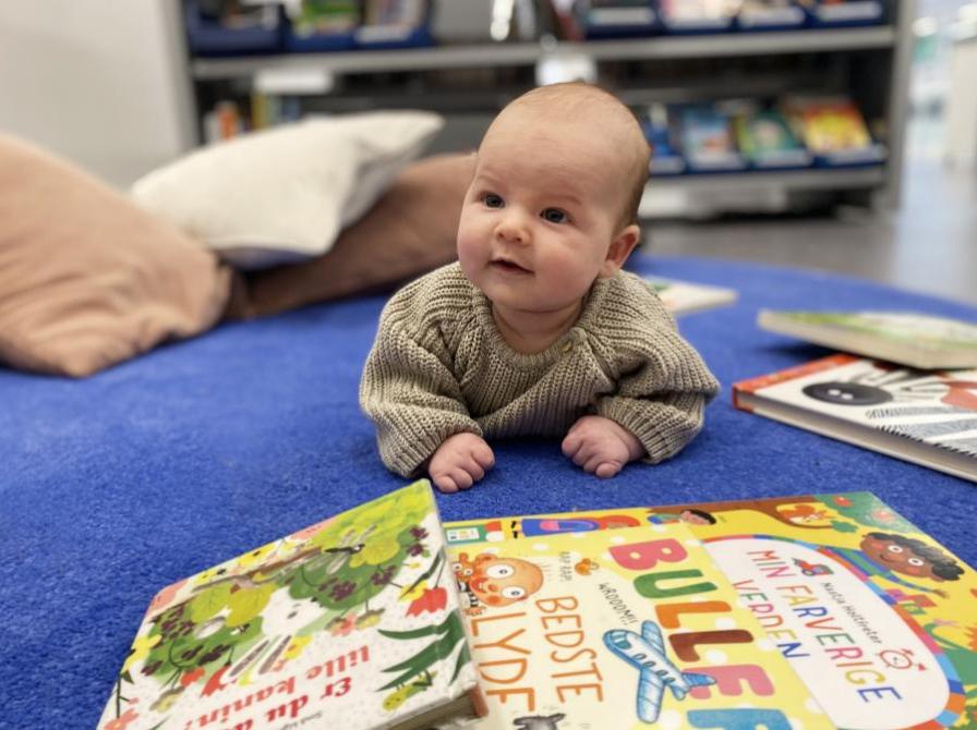 baby ligger på gulv med pegebøger