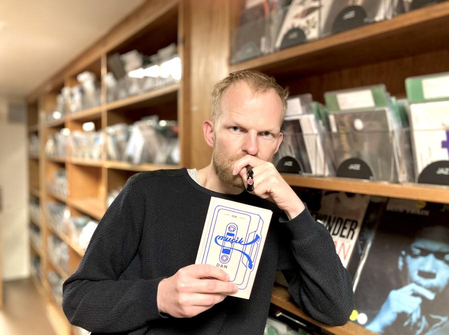 Biblioteket kulturformidler Morten står med bogen 'Om Musik' af Dan Turell